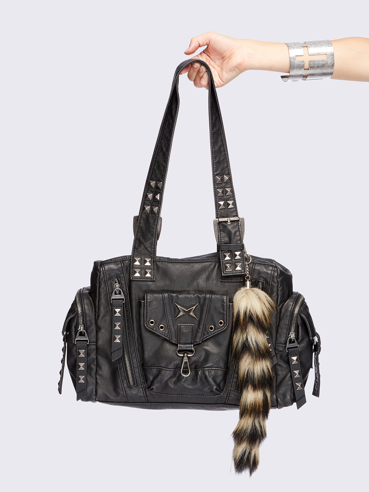 Black faux leather shoulder bag with pyramid studs, metal hardware details and removable faux fur fox tail keychain.