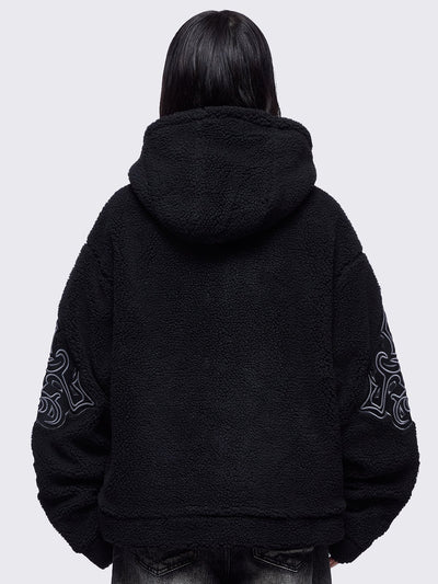 Black fleece hoodie jacket featuring a cross patch on front and sleeves and silver stud details.
