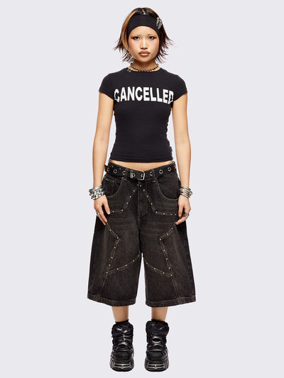 Black washed longline denim shorts with star-shaped stud and seam detail on front.