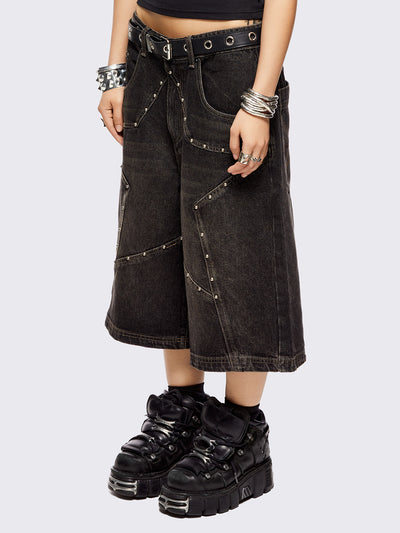 Black washed longline denim shorts with star-shaped stud and seam detail on front.