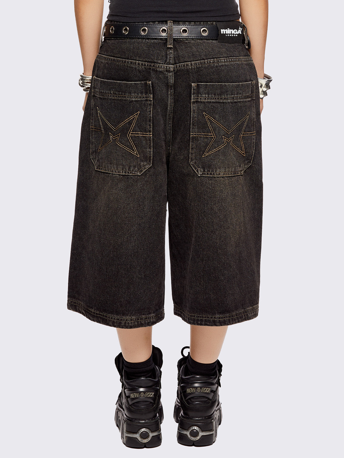 Black washed longline denim shorts with star-shaped stud and seam detail on front.