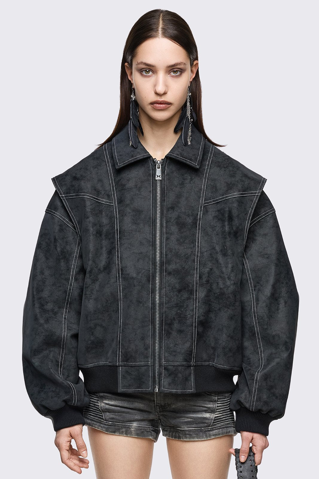 Black faux leather bomber jacket with white contrast stitching, layered sleeves and oversized grunge fit.