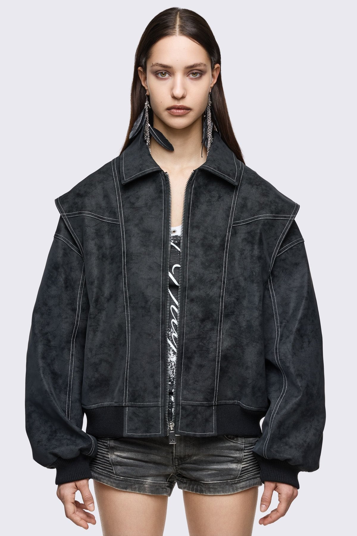 Black faux leather bomber jacket with white contrast stitching, layered sleeves and oversized grunge fit.