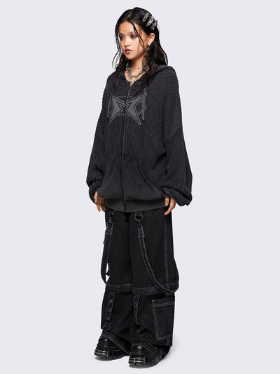 Black washed oversized hoodie cardigan featuring a signature graphic front print. Designed with a chunky ribbed knit, drawstring hood, zip fastening, and kangaroo pockets. The drop shoulders and long sleeves enhance its relaxed, streetwear-inspired fit.