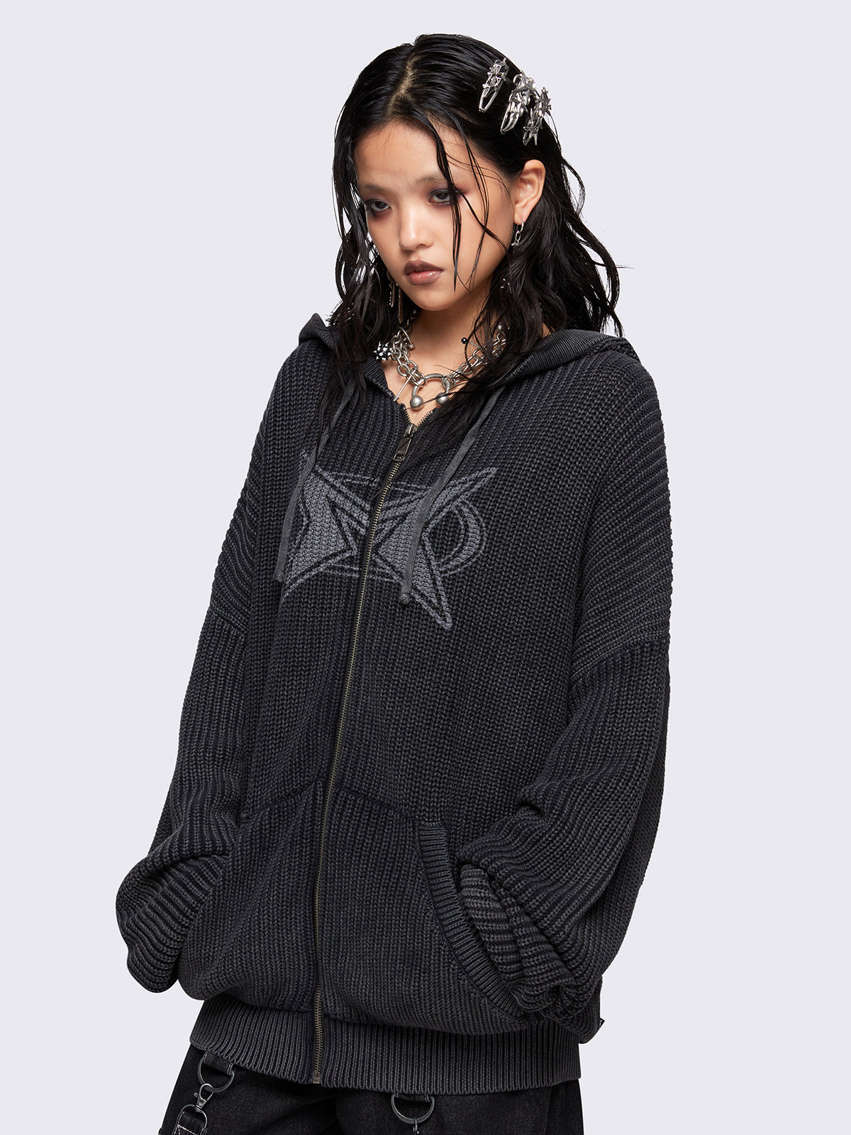 Black washed oversized hoodie cardigan featuring a signature graphic front print. Designed with a chunky ribbed knit, drawstring hood, zip fastening, and kangaroo pockets. The drop shoulders and long sleeves enhance its relaxed, streetwear-inspired fit.