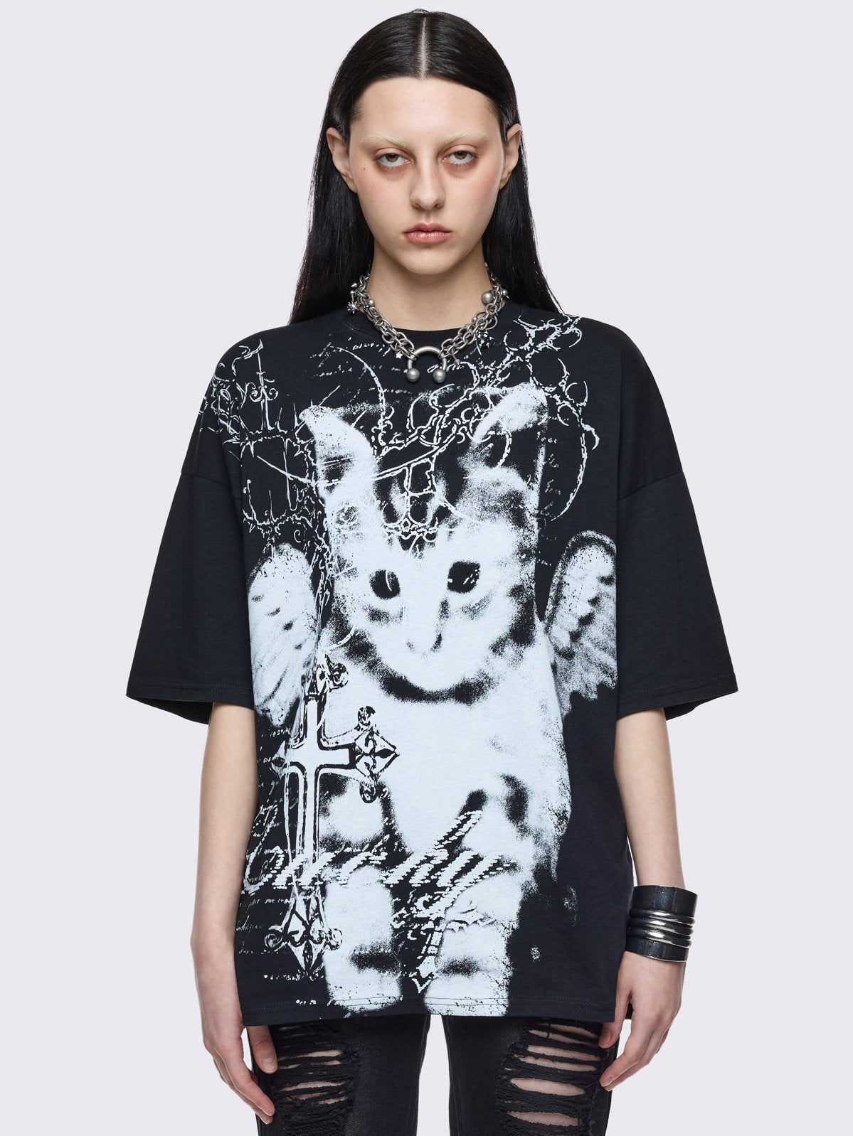 Black oversize graphic t-shirt with winged cat and crosses graphic front print.