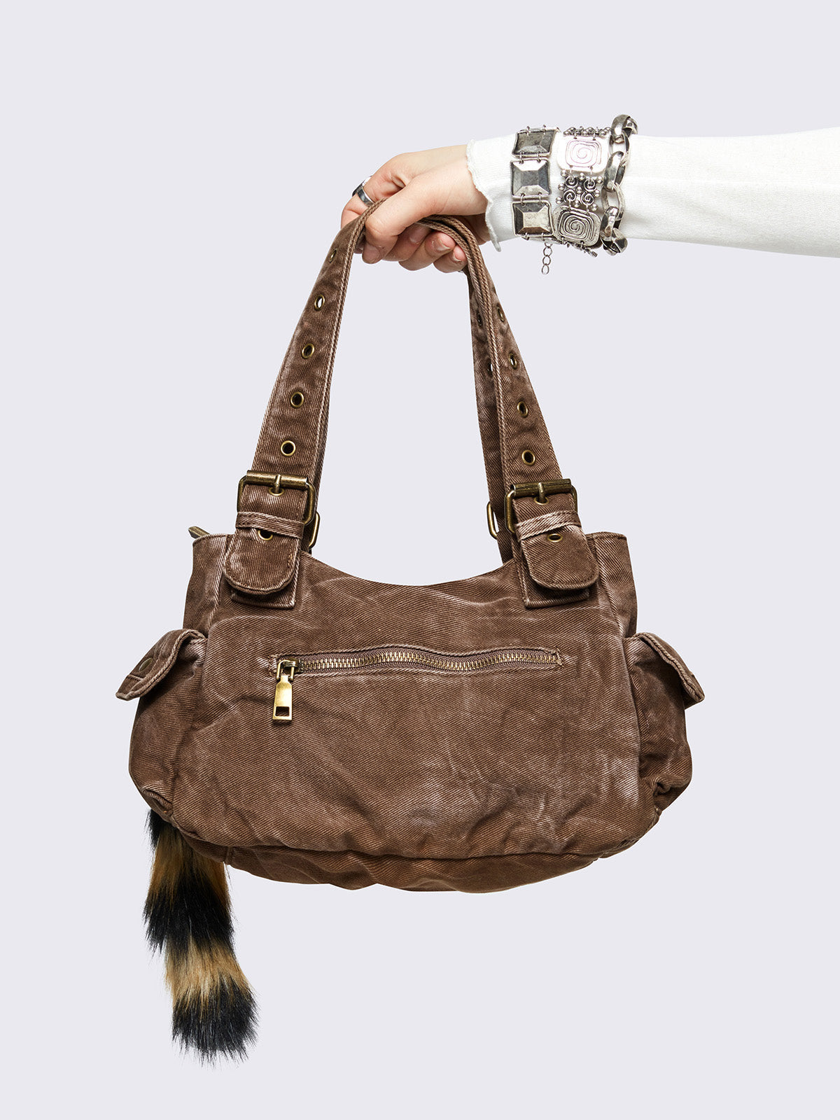Brown washed denim buckle shoulder bag with removable faux fur fox tail keychain, multiple pockets and brass studs details.