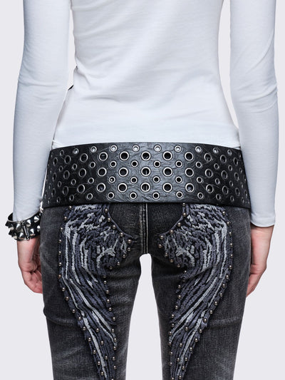 Wide black faux leather belt with multiple silver grommets/eyelets across the width, secured by a large triple-pin buckle, with a detachable star charm.