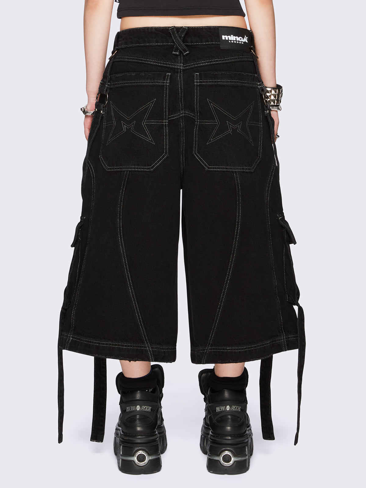 Black washed cargo jorts with multiple utility pockets, contrast white stitching, straps and metal hardware details.