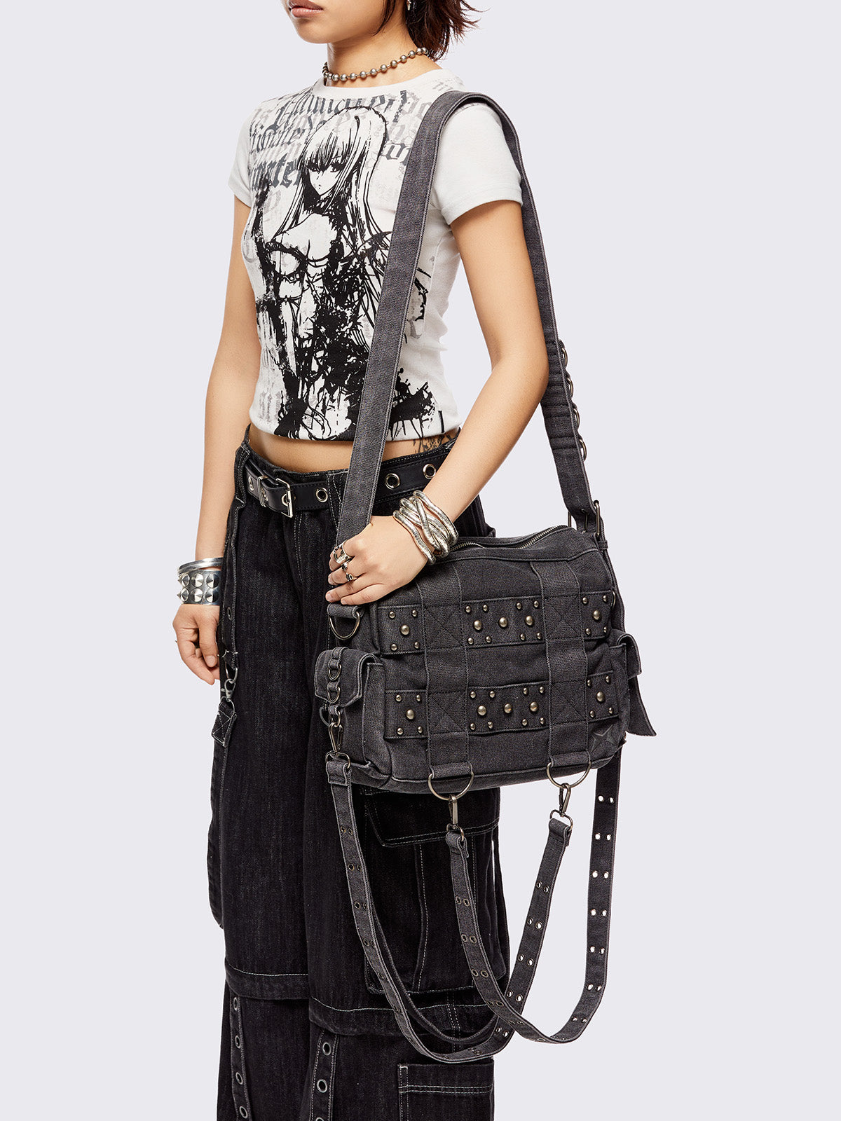 Grey washed denim crossbody bag with all over straps, studs and silver hardware details.