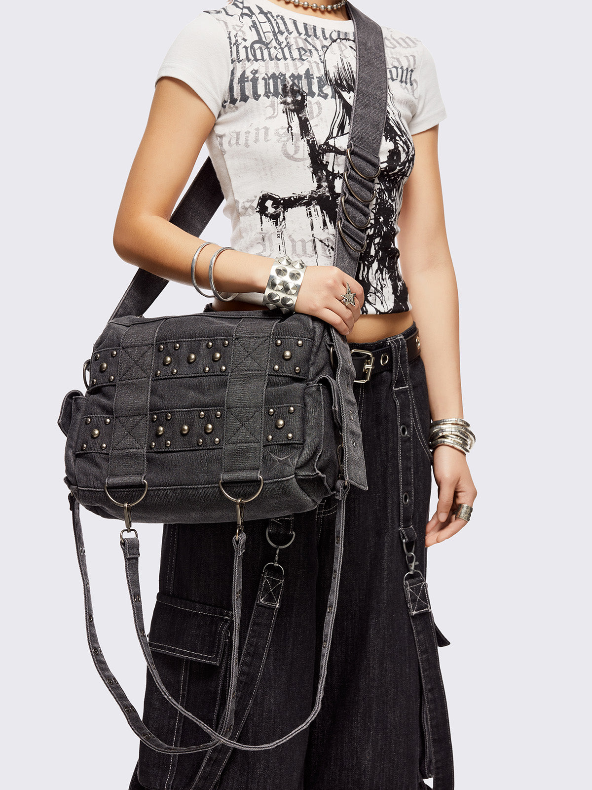 Grey washed denim crossbody bag with all over straps, studs and silver hardware details.