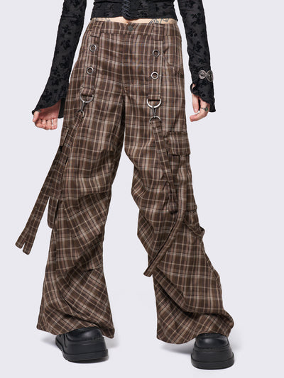 Brown plaid multi-pocket cargo pants with wide legs, featuring straps, eyelets, and D-ring details for a stylish utility-inspired look.