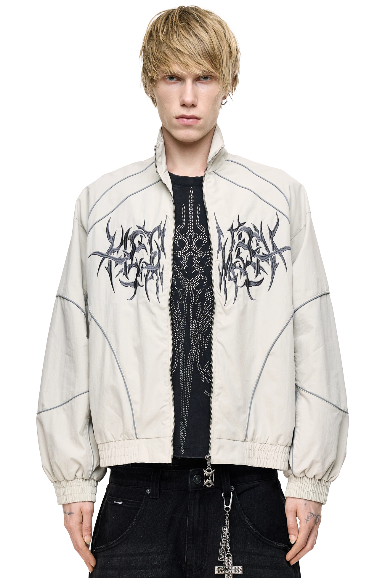 Grey windbreaker jacket with reflective piped seams, sigilism embroidery, zip pockets and a relaxed fit.