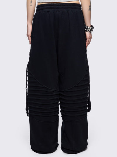 Black wide leg sweatpants featuring moto pintuck panels and lace-up details. 
