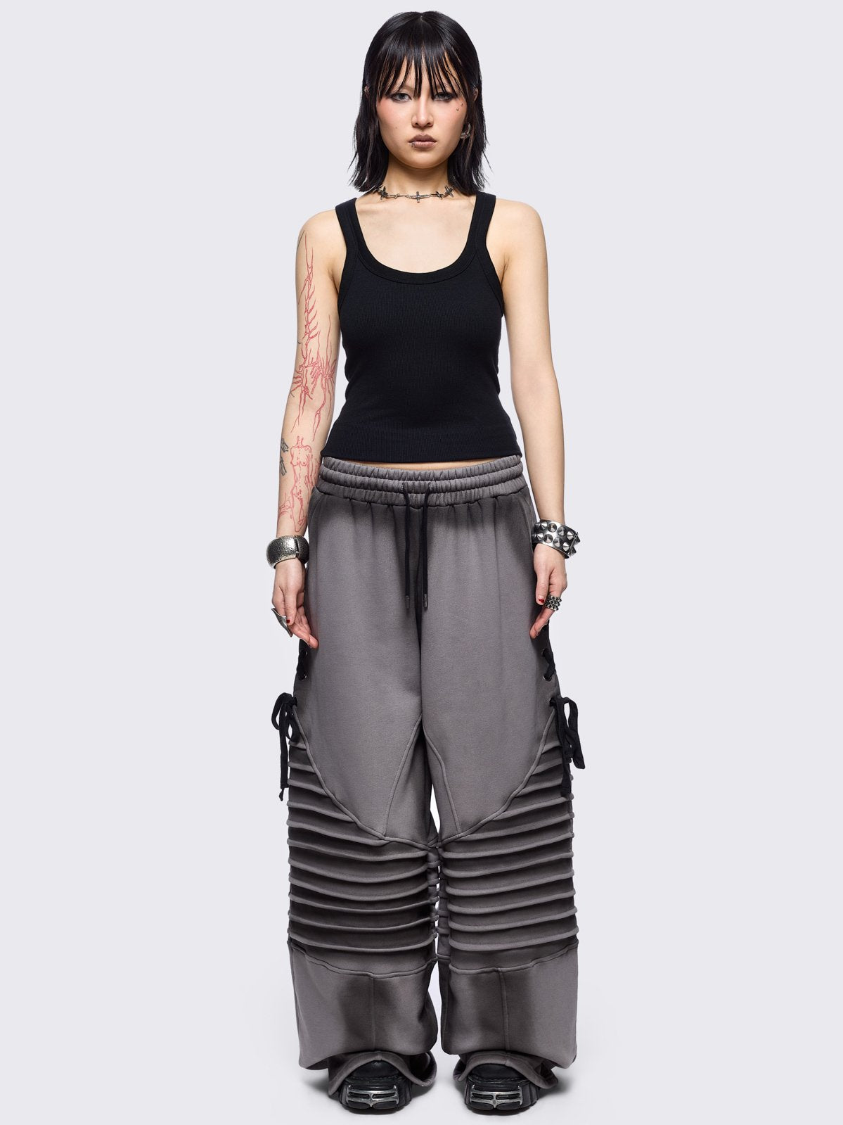 Grey washed wide leg sweatpants featuring moto pintuck panels, lace-up details and black fade out.