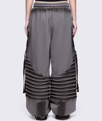 Grey washed wide leg sweatpants featuring moto pintuck panels, lace-up details and black fade out.