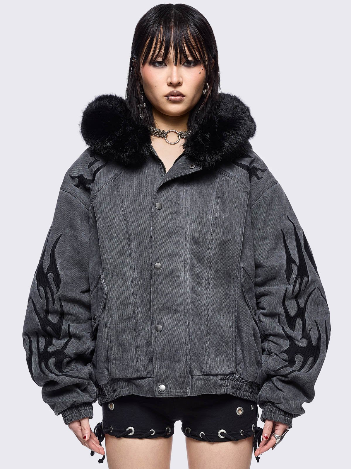 Grey washed denim bomber jacket featuring black sigilism patches and black faux fur hood.