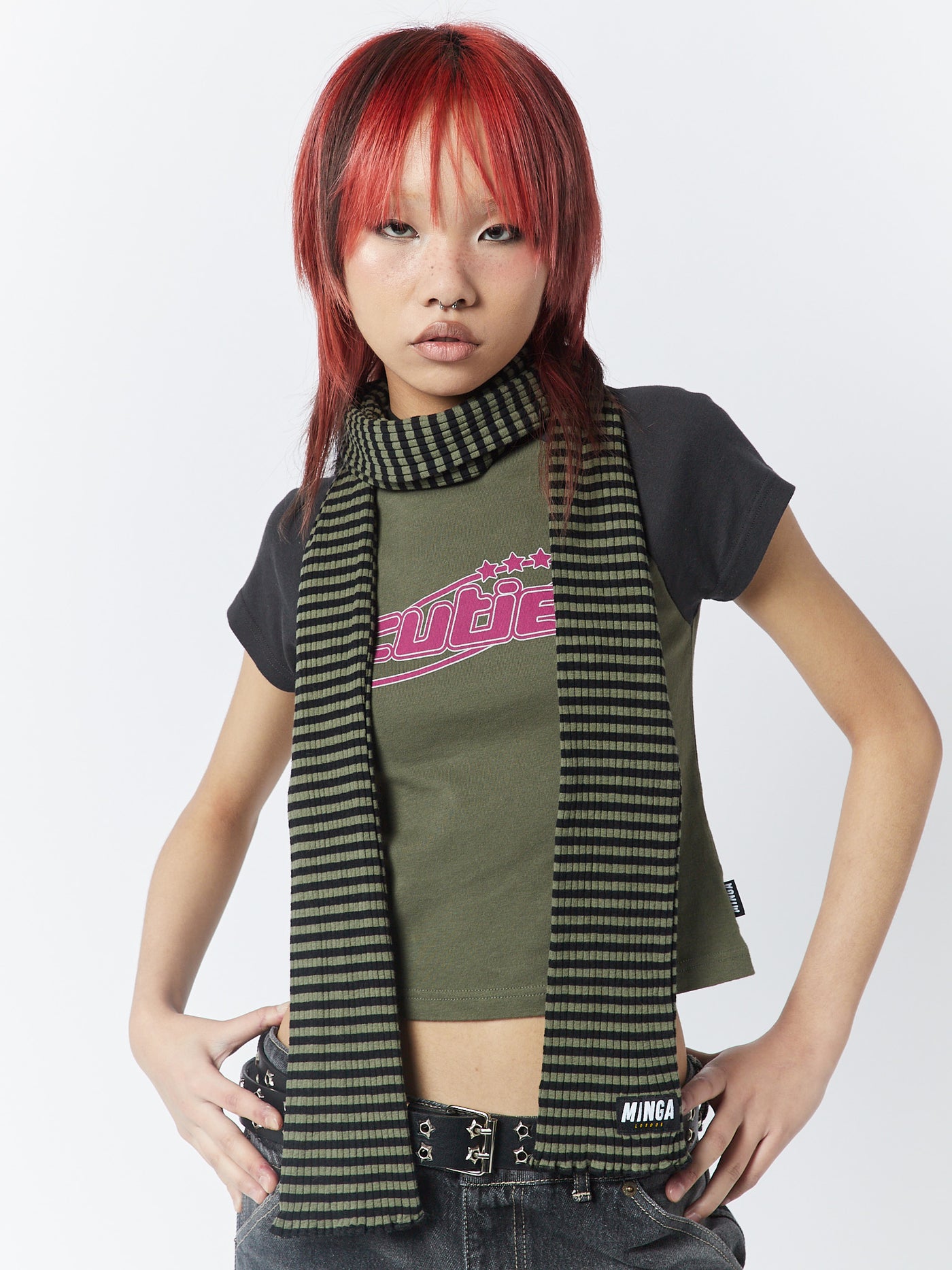 A green and black striped scarf by Minga London. This girlfriend-style scarf adds a trendy and stylish touch to any outfit with its bold stripes and versatile color combination.