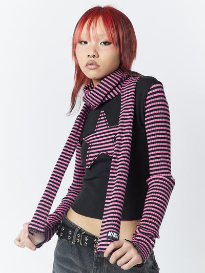 A pink and black striped scarf by Minga London. This scarf combines a trendy color combination with classic stripes, offering a stylish and versatile accessory to elevate your outfit.