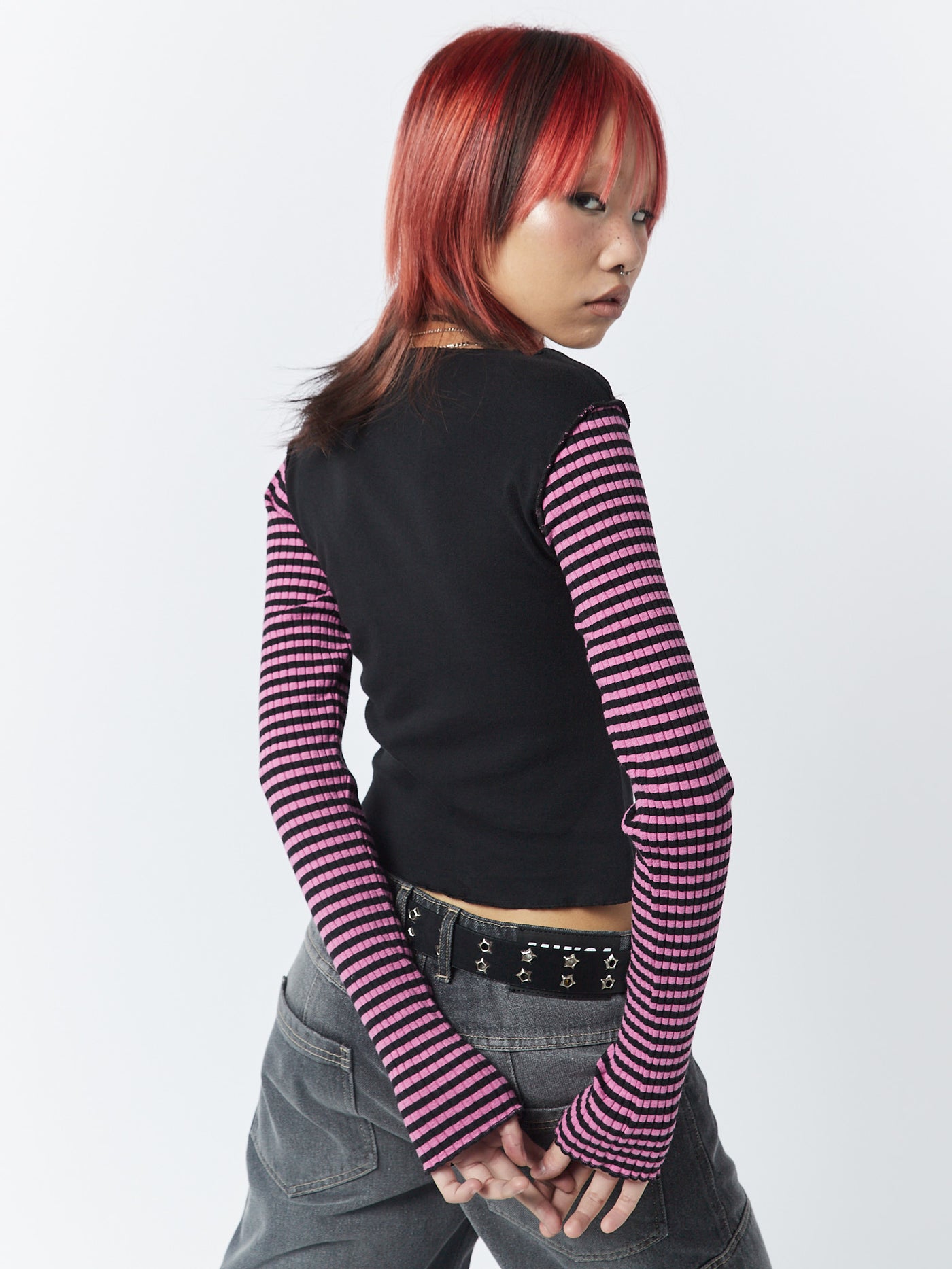 A long sleeve top with pink and black stripes by Minga London. This top features a star patch, adding a unique and eye-catching detail to the overall design.