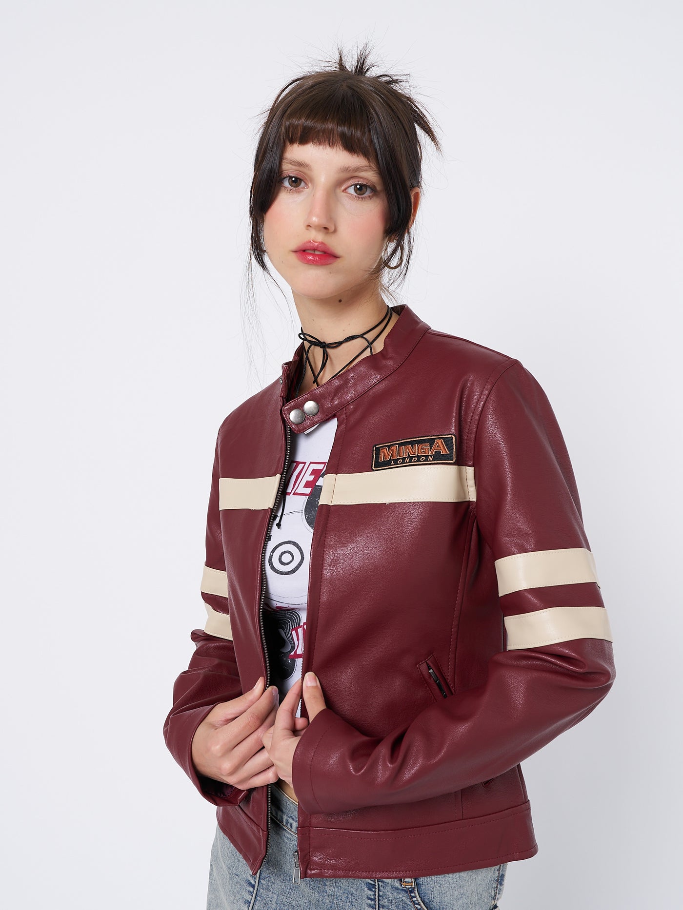 Dark red vegan leather racer jacket with beige contrast stripes. Snap button collar, Minga logo detail, zipped cuffs and pockets.