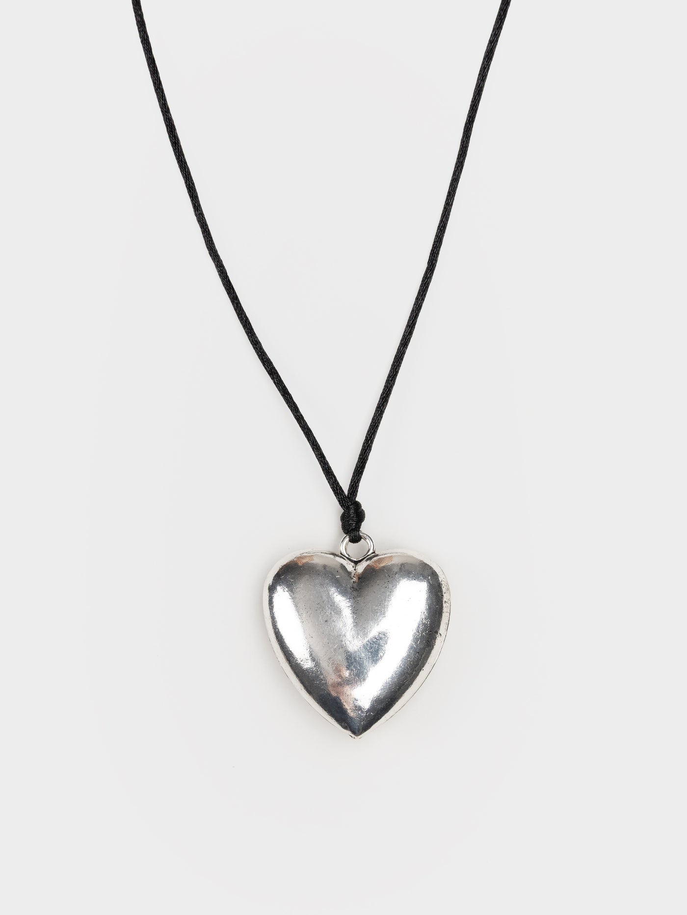 A grunge-inspired silver necklace with a captivating heart pendant, embodying a rebellious and edgy style.