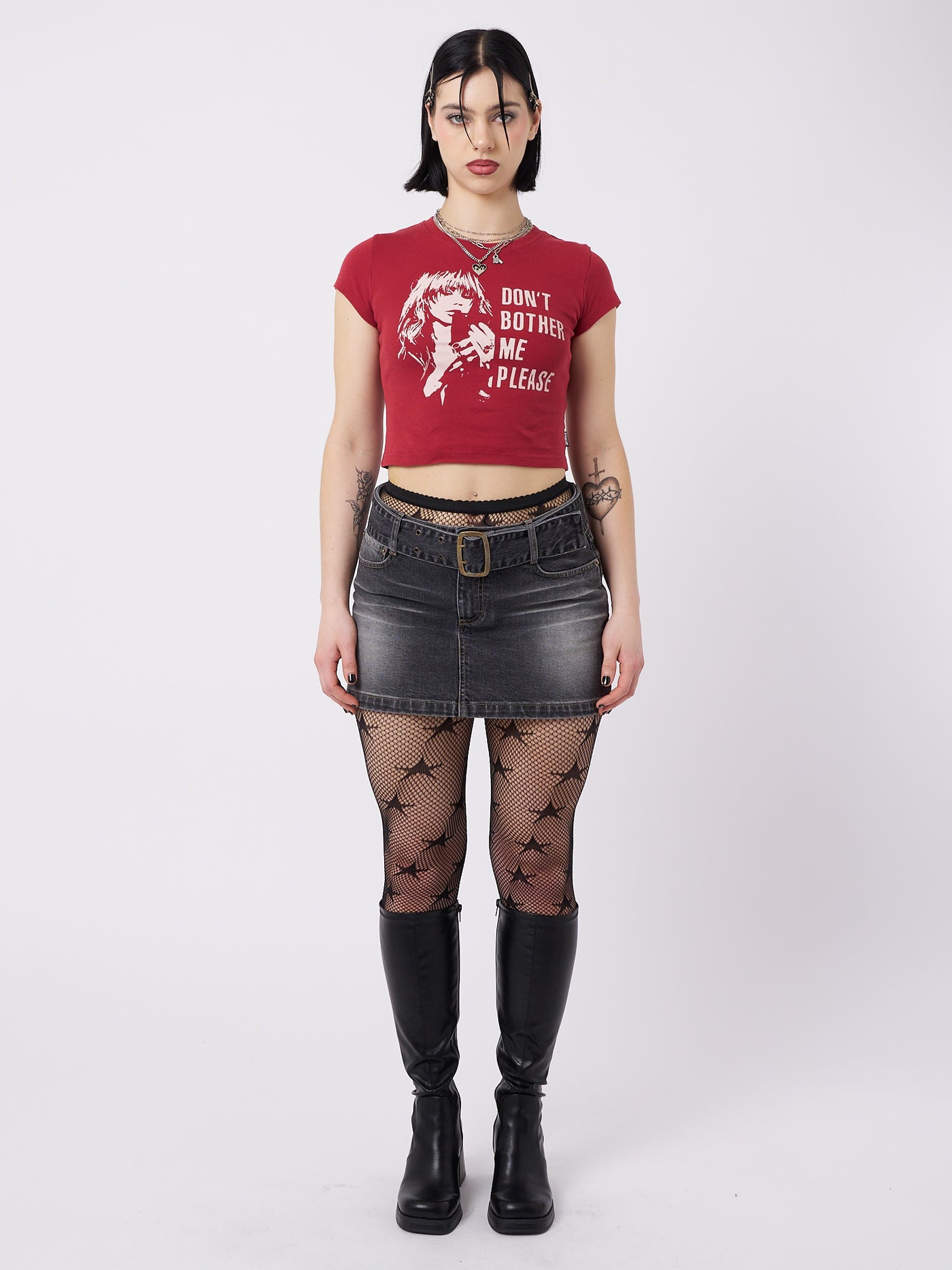 A red baby tee with the text "Don't Bother Me Plz" by Minga London. This tee exudes a cool and laid-back vibe, making a bold statement while adding a touch of attitude to your outfit.