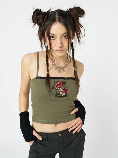 A dark khaki cami top featuring an embroidered enoki mushroom design by Minga London. This top adds a touch of nature-inspired style to your outfit, with its intricately embroidered mushroom.