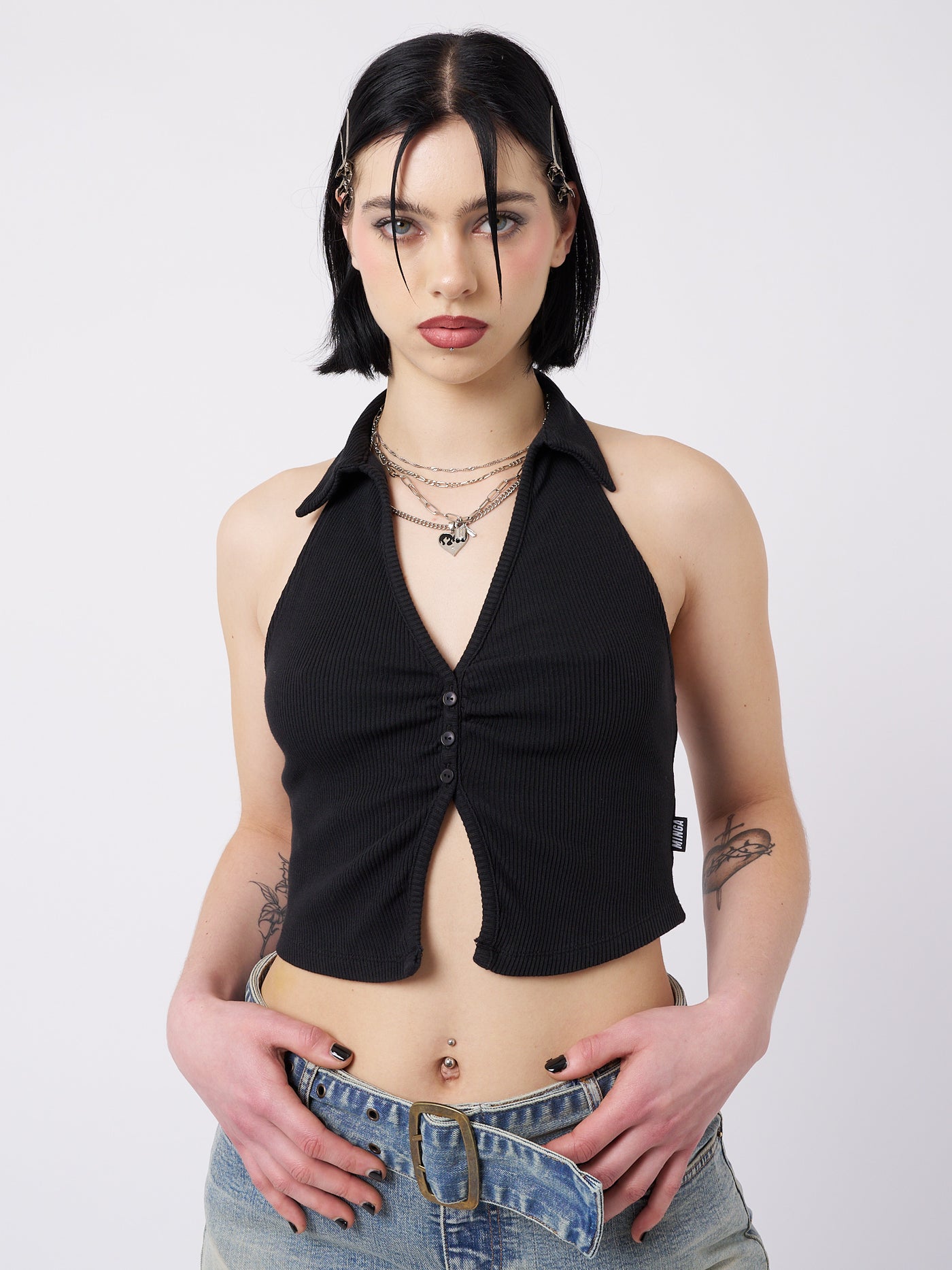 A black halter neck collar top named Raya by Minga London. This top showcases a cool and feminist-inspired design, combining a sleek halter neck and collar detail for a bold and empowering look